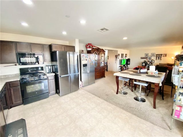 kitchen featuring appliances with stainless steel finishes, light carpet, and dark brown cabinetry