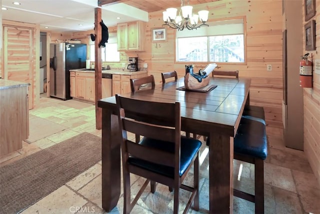 dining space featuring a chandelier and wood walls