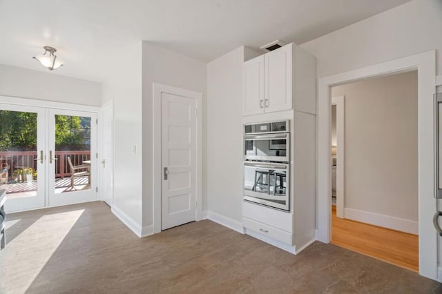 kitchen featuring double oven, french doors, white cabinets, and light wood-type flooring