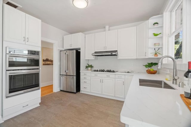 kitchen with stainless steel appliances, sink, white cabinets, and light stone counters