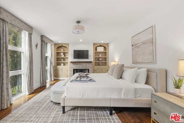 bedroom with a fireplace, hardwood / wood-style floors, and multiple windows