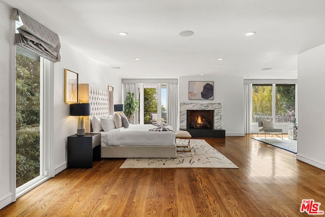 bedroom featuring hardwood / wood-style flooring, a fireplace, and multiple windows