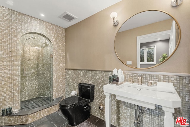 bathroom with tile patterned flooring, a tile shower, tile walls, and toilet