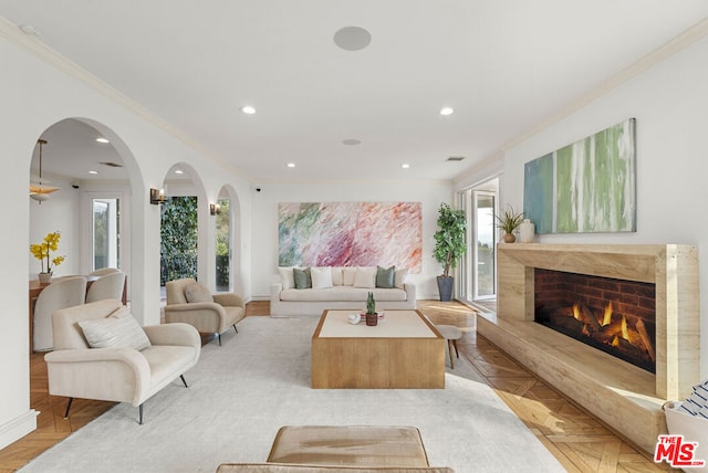 living room featuring crown molding, a high end fireplace, and light parquet floors