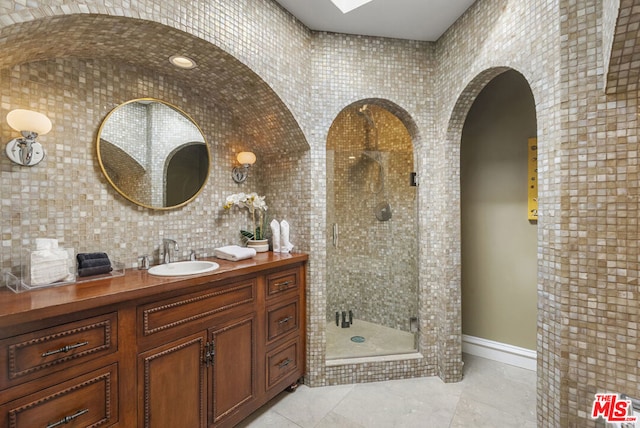 bathroom with tile walls, an enclosed shower, vanity, tasteful backsplash, and tile patterned floors