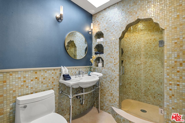 bathroom with toilet, tile walls, and a shower with shower door