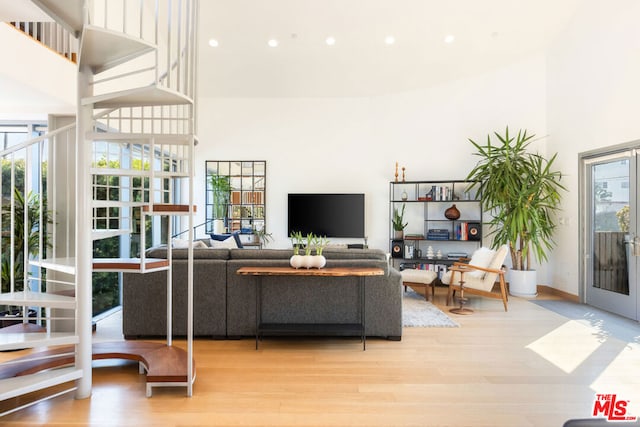 living room with french doors, light hardwood / wood-style floors, and a high ceiling