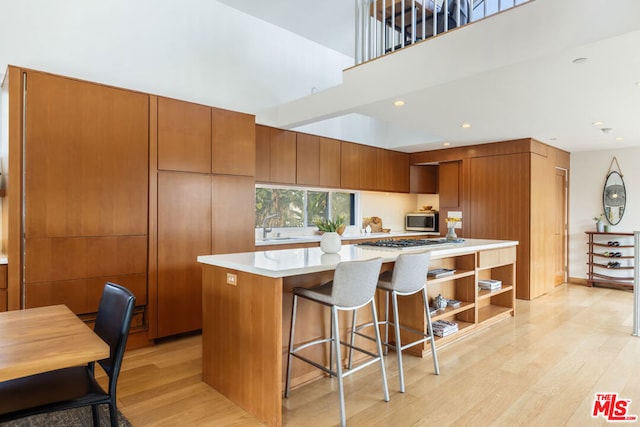 kitchen featuring sink, light hardwood / wood-style flooring, a breakfast bar area, appliances with stainless steel finishes, and a kitchen island