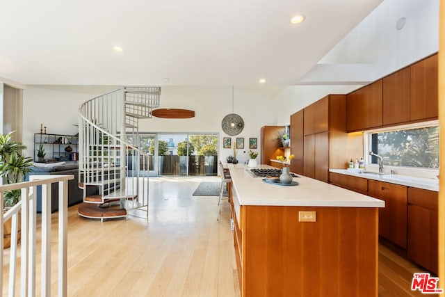 kitchen with stainless steel gas stovetop, a kitchen island, sink, and light hardwood / wood-style floors