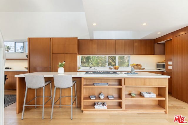 kitchen with a kitchen island, appliances with stainless steel finishes, a breakfast bar, and light wood-type flooring