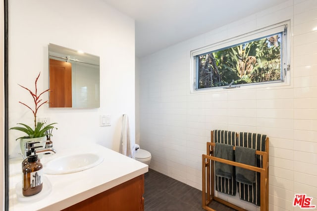 bathroom featuring tile patterned floors, toilet, tile walls, vanity, and radiator