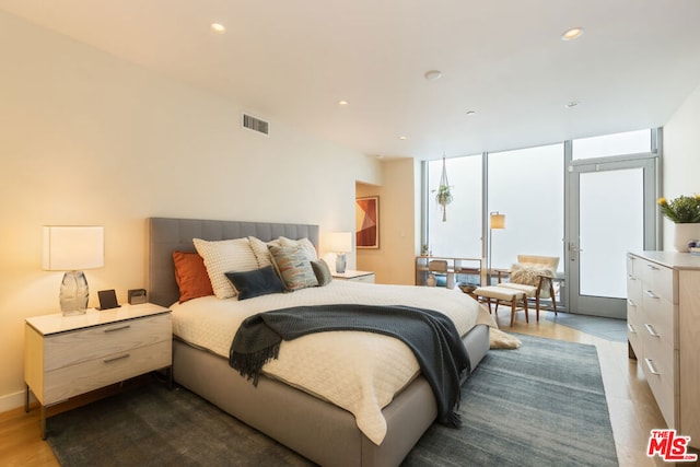 bedroom featuring expansive windows and dark hardwood / wood-style floors