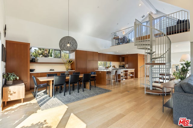 dining space featuring beam ceiling, light hardwood / wood-style flooring, and high vaulted ceiling