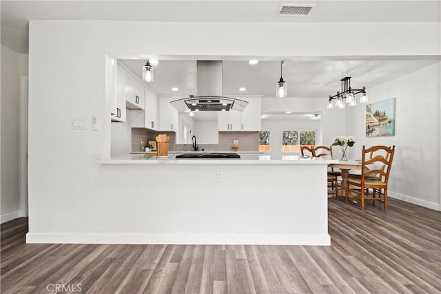 kitchen featuring island exhaust hood, decorative light fixtures, white cabinets, and kitchen peninsula