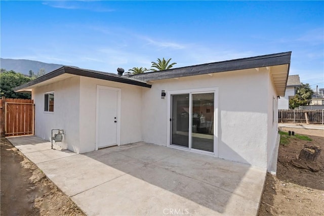 back of property with a mountain view and a patio area