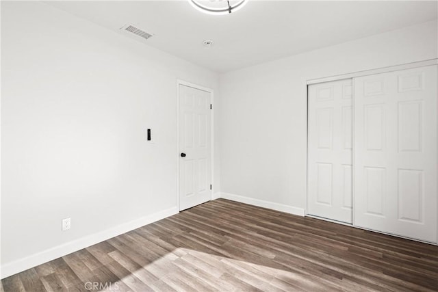 unfurnished bedroom featuring dark wood-type flooring and a closet