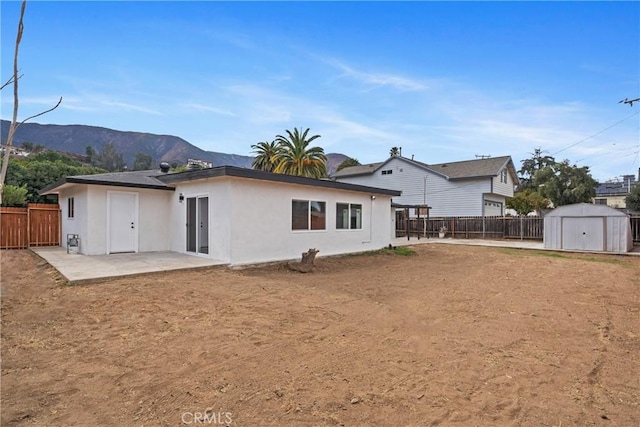 back of property with a storage shed, a mountain view, and a patio