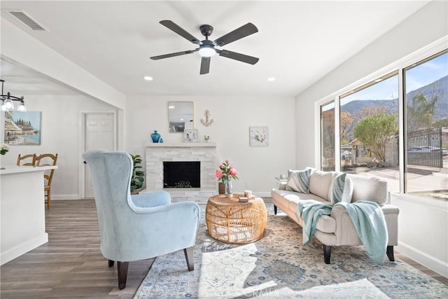 living room with wood-type flooring, a mountain view, ceiling fan, and a brick fireplace