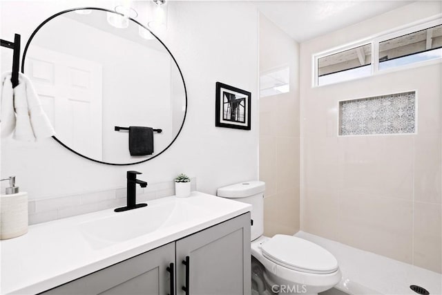 bathroom featuring vanity, toilet, and a tile shower