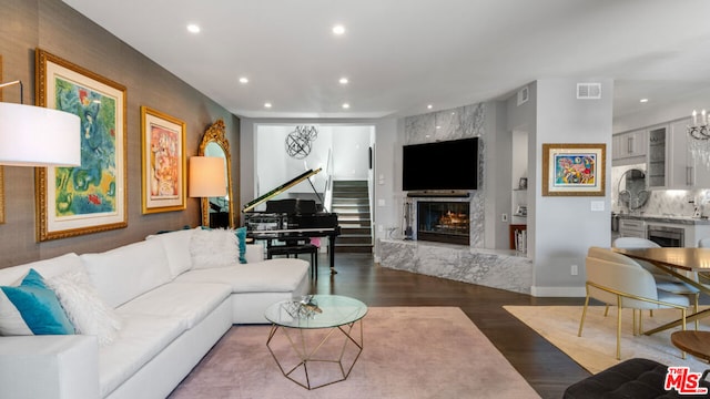 living room featuring dark hardwood / wood-style flooring, wine cooler, a high end fireplace, and a chandelier