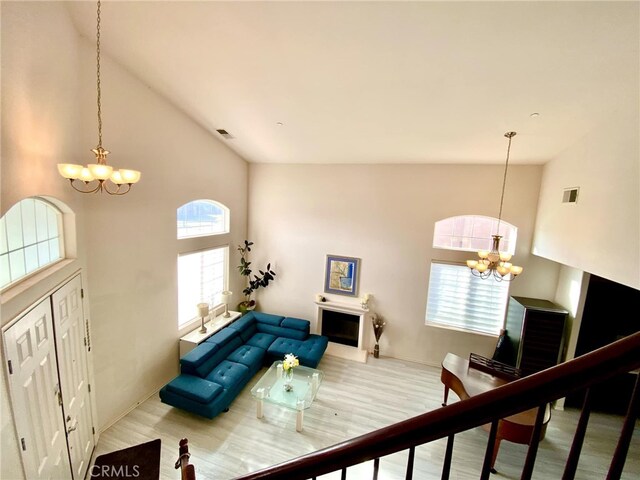 living room with high vaulted ceiling, a healthy amount of sunlight, and an inviting chandelier