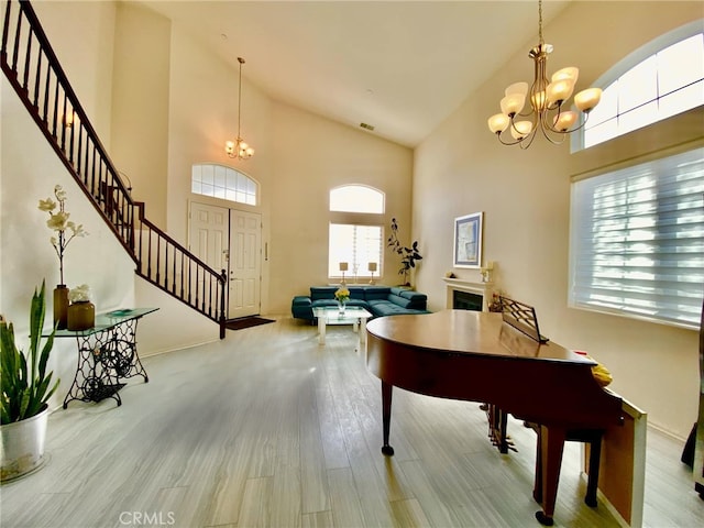 entrance foyer with an inviting chandelier, a towering ceiling, and light wood-type flooring