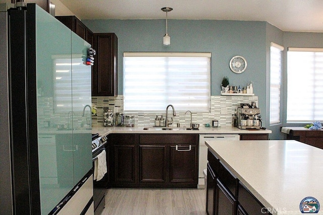 kitchen featuring freestanding refrigerator, hanging light fixtures, light countertops, black electric range, and a sink