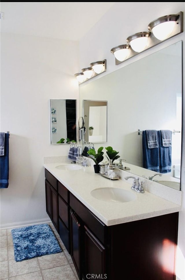 full bathroom with double vanity, baseboards, a sink, and tile patterned floors