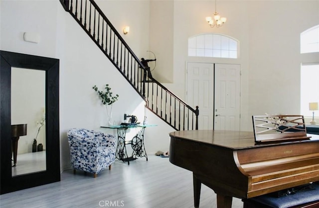 entrance foyer featuring stairs, a towering ceiling, an inviting chandelier, and wood finished floors