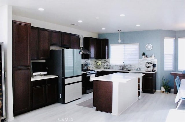 kitchen with a center island, hanging light fixtures, freestanding refrigerator, light countertops, and stainless steel stove