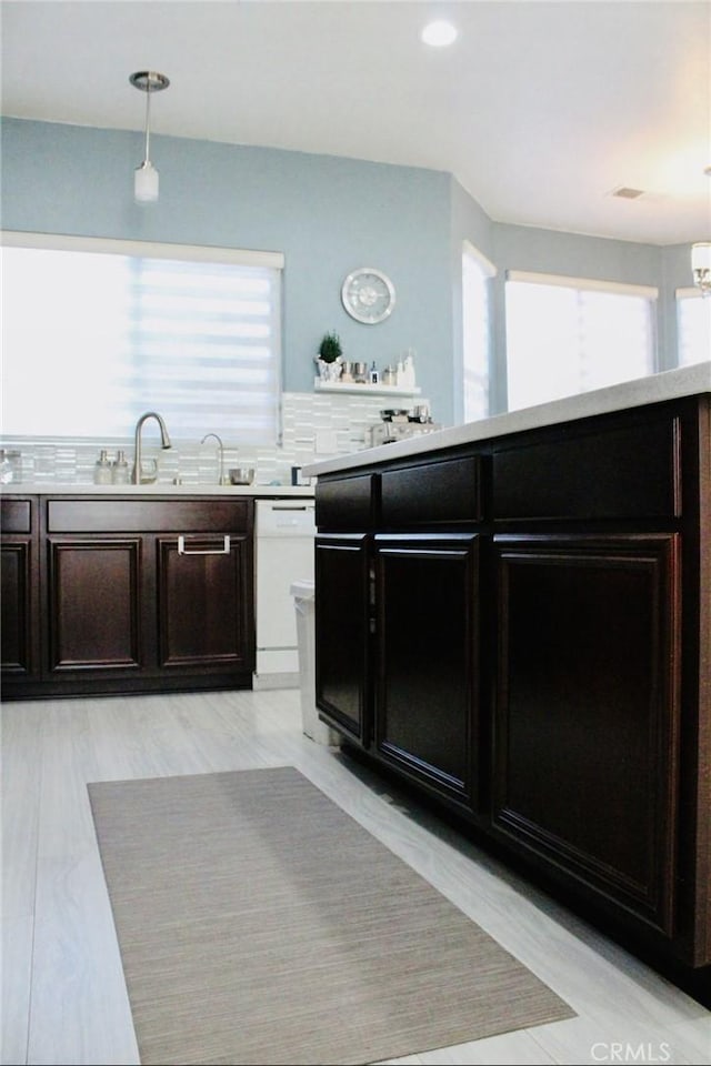 kitchen featuring dishwasher, light countertops, dark brown cabinetry, and a healthy amount of sunlight