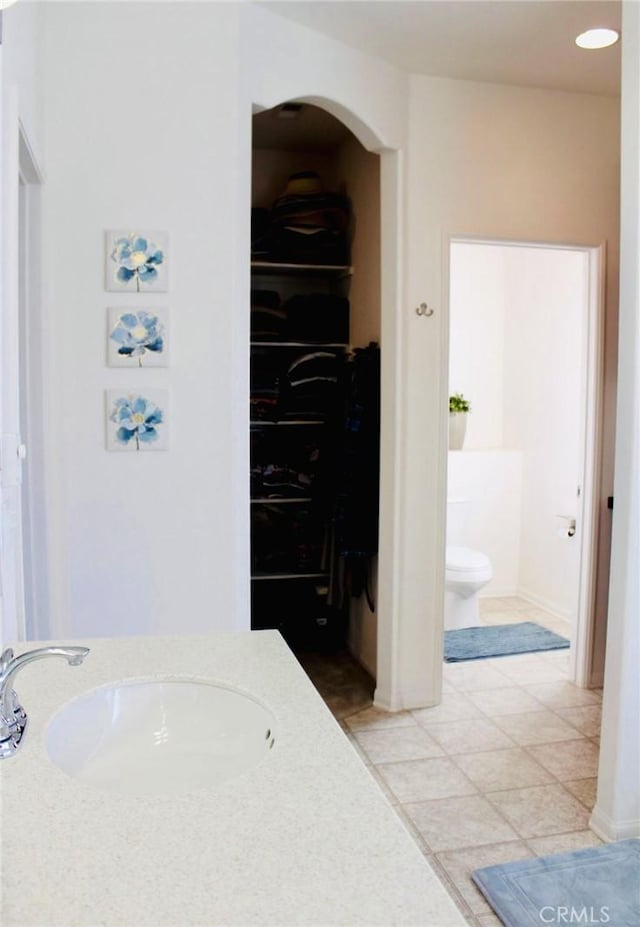 bathroom with a closet, vanity, toilet, and tile patterned floors