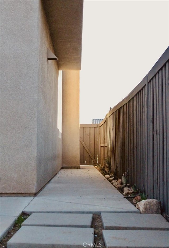 view of side of home featuring fence and stucco siding