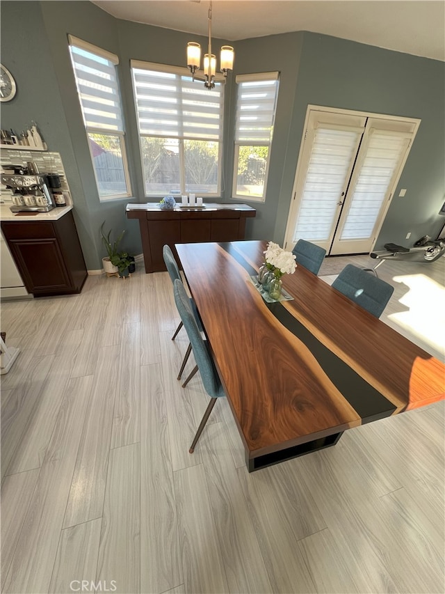 dining space with baseboards, light wood finished floors, and an inviting chandelier