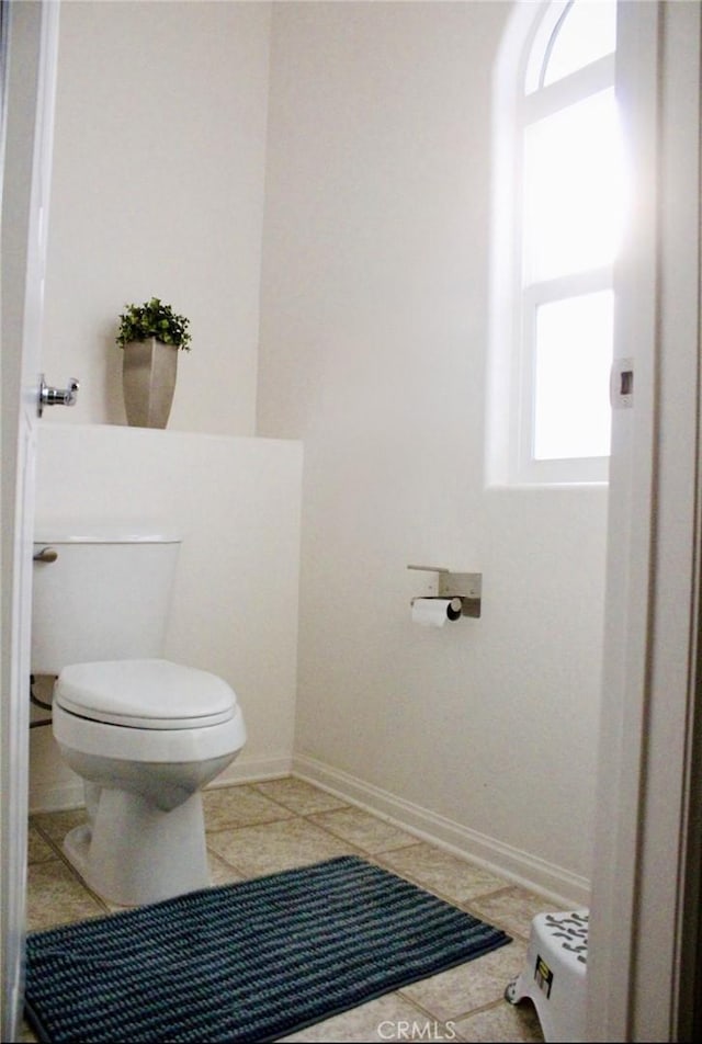 bathroom featuring tile patterned flooring, baseboards, and toilet