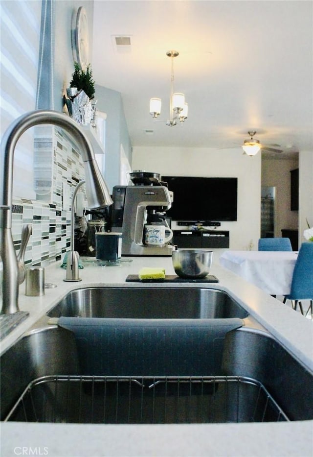 kitchen with light countertops, tasteful backsplash, visible vents, and an inviting chandelier