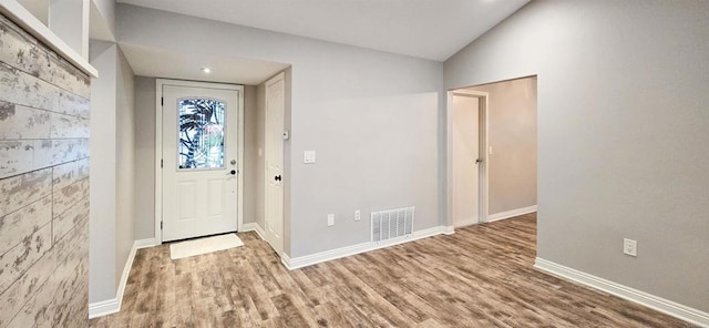 foyer with visible vents, lofted ceiling, baseboards, and wood finished floors