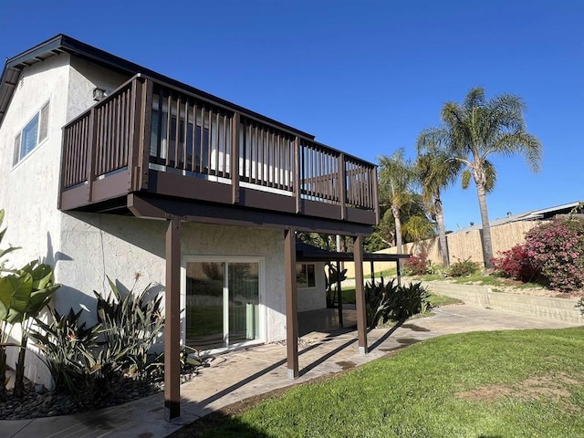 rear view of house featuring stucco siding, a patio, and a yard