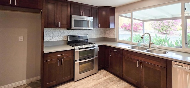 kitchen with light wood-style flooring, a sink, stainless steel appliances, light countertops, and dark brown cabinets