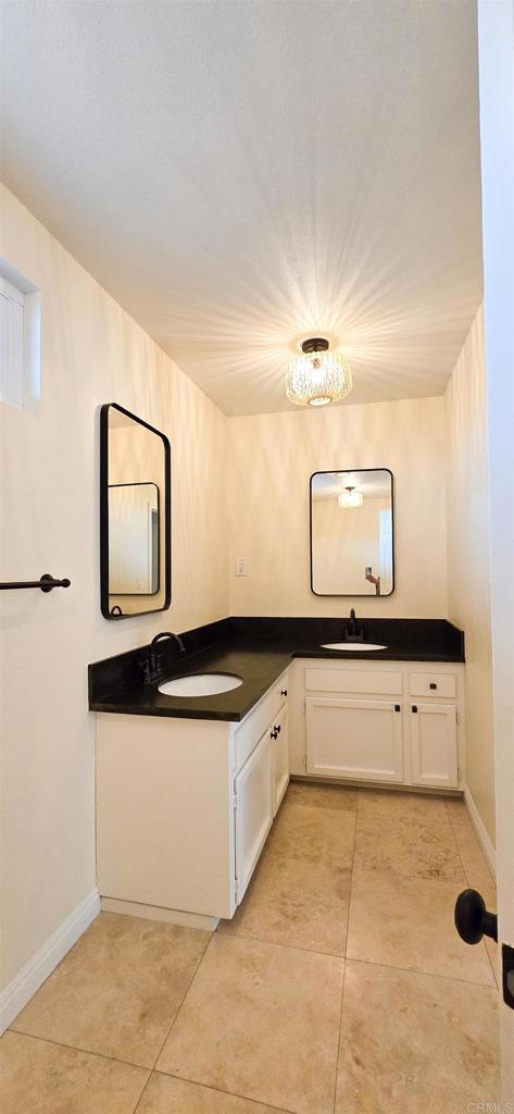 kitchen featuring white cabinetry, dark countertops, light tile patterned floors, and a sink