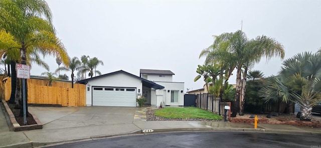 view of front of property featuring a front yard, fence, driveway, an attached garage, and stucco siding