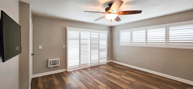 empty room with heating unit, a ceiling fan, baseboards, and wood finished floors