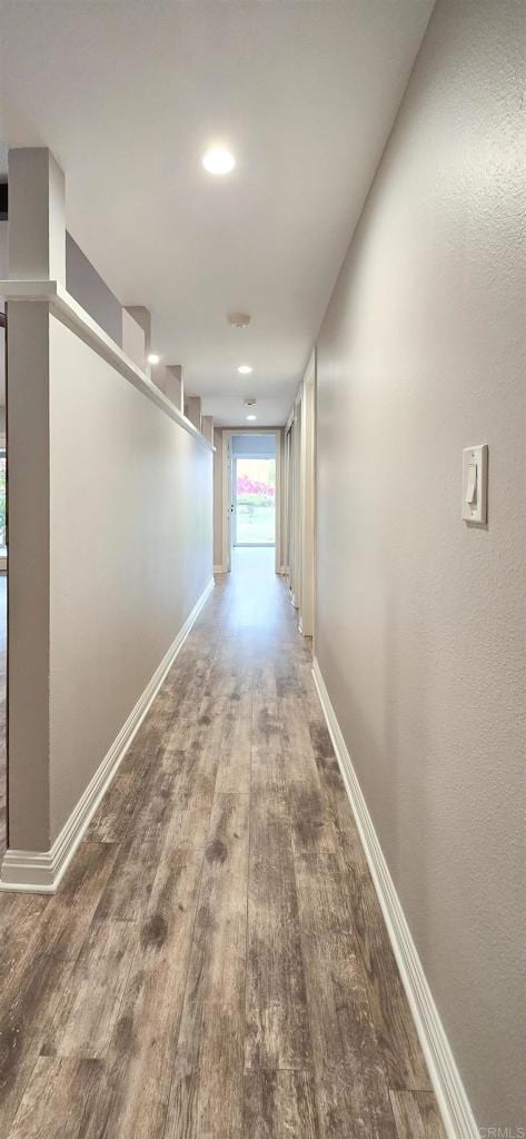 corridor featuring baseboards and wood finished floors