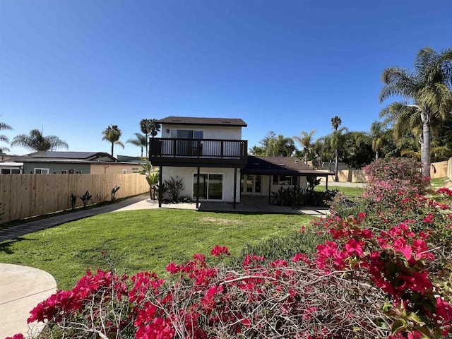 rear view of house with a patio, a lawn, and a fenced backyard