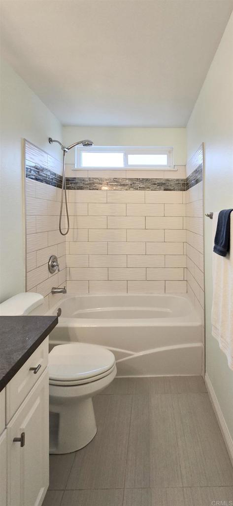 full bathroom with vanity, toilet, tub / shower combination, and baseboards