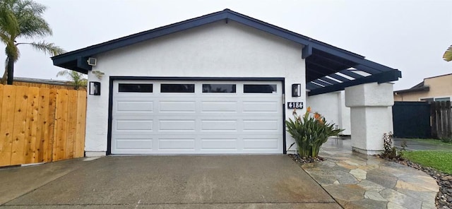 garage featuring concrete driveway and fence