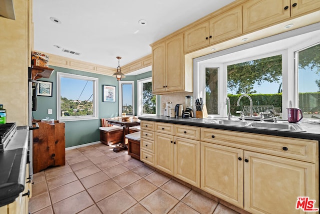 kitchen with hanging light fixtures, sink, light tile patterned floors, and light brown cabinets