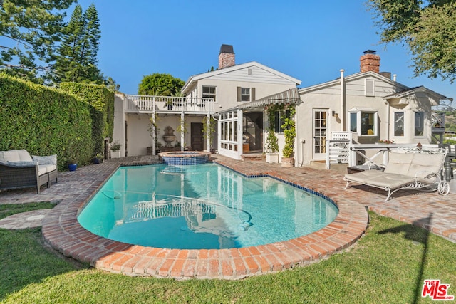 rear view of house featuring a swimming pool with hot tub and a patio area