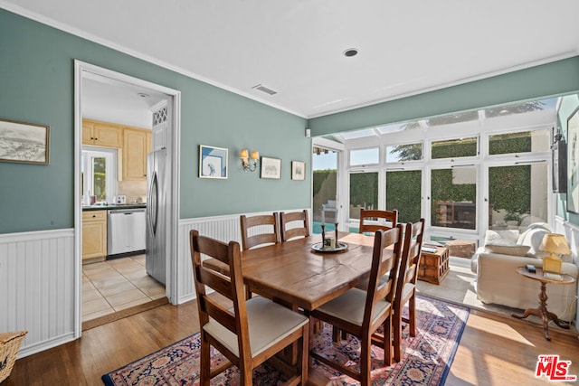 dining space with crown molding, plenty of natural light, and light hardwood / wood-style floors