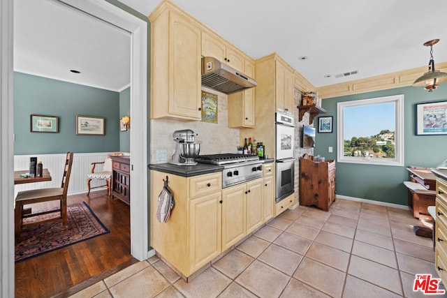 kitchen featuring appliances with stainless steel finishes, pendant lighting, light brown cabinetry, decorative backsplash, and light tile patterned floors